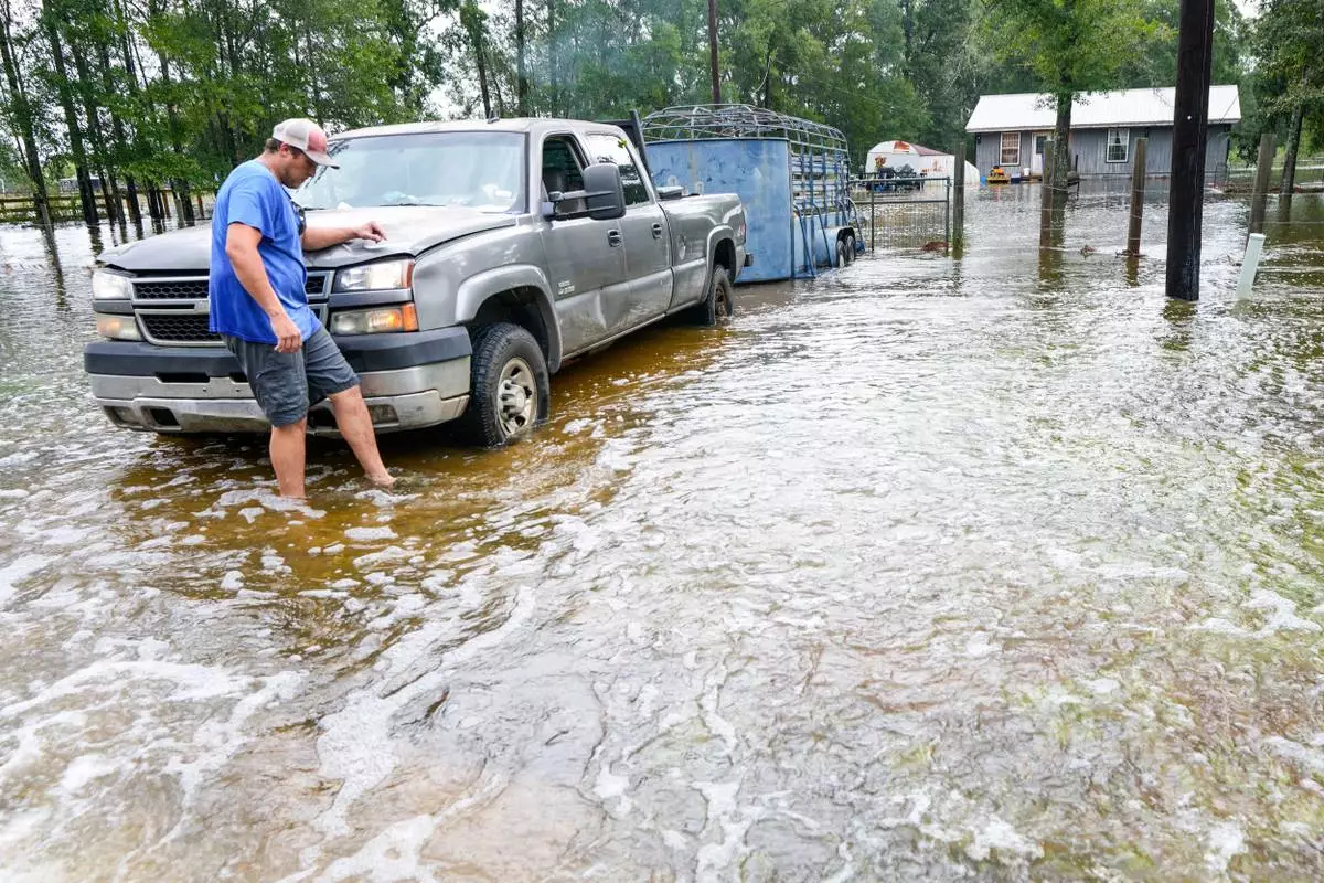 Chase Barfield walks to his truck as he takes belongings and his dogs away from floodwaters around his house in the aftermath of Tropical Storm Edouard near Honey Island, Texas, Wednesday, Sept. 2, 2026. (Brett Coomer/Houston Chronicle via AP)