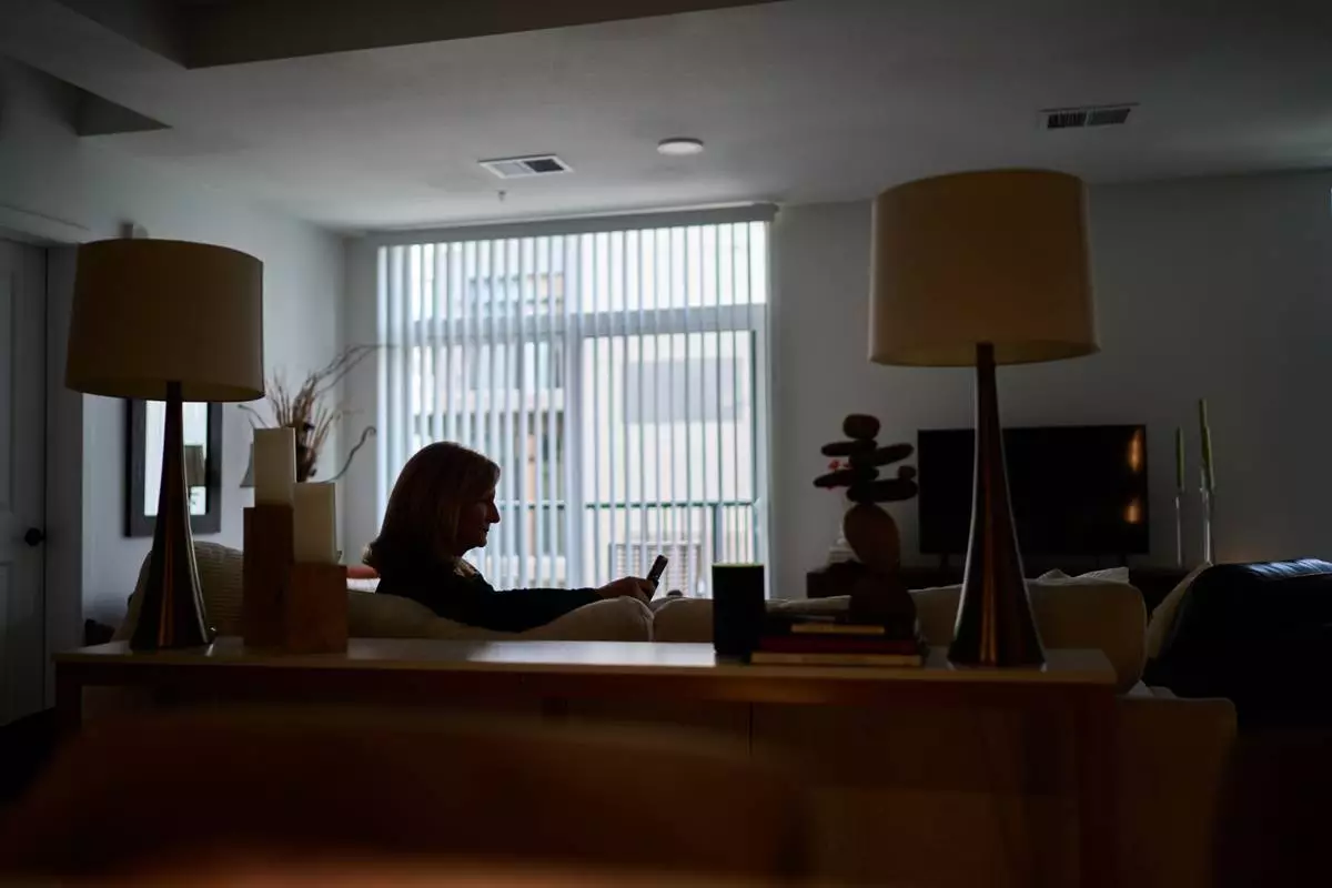 Debra Fox, who had $58,000 stolen from her in a romance scam, looks at her phone, Wednesday, May 13, 2026, at her home in Arvada, Colo. (AP Photo/David Goldman)