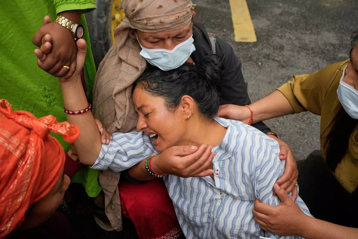 Relatives console Muna Khadka, center, who lost her son Aayush Khada in flash floods, at a cremation ground in Chitwan, Nepal, Monday, Aug. 31, 2026. (AP Photo/Dar Yasin) CORRECTION: Corrects to clarify that this was at a separate cremation ground and not during a mass burial.