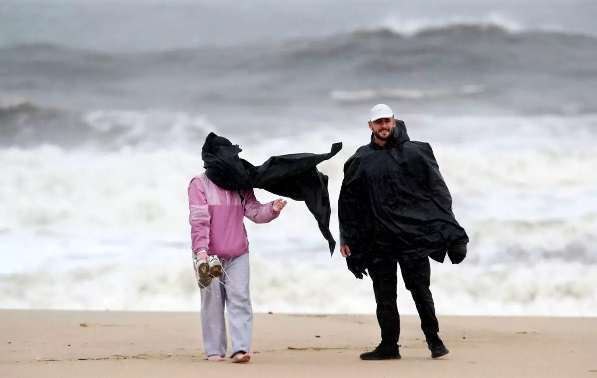 A woman loses control of her poncho while strolling along the beach, Saturday, Sept. 26, 2026, in Asbury Park, N.J. (AP Photo/Noah K. Murray)