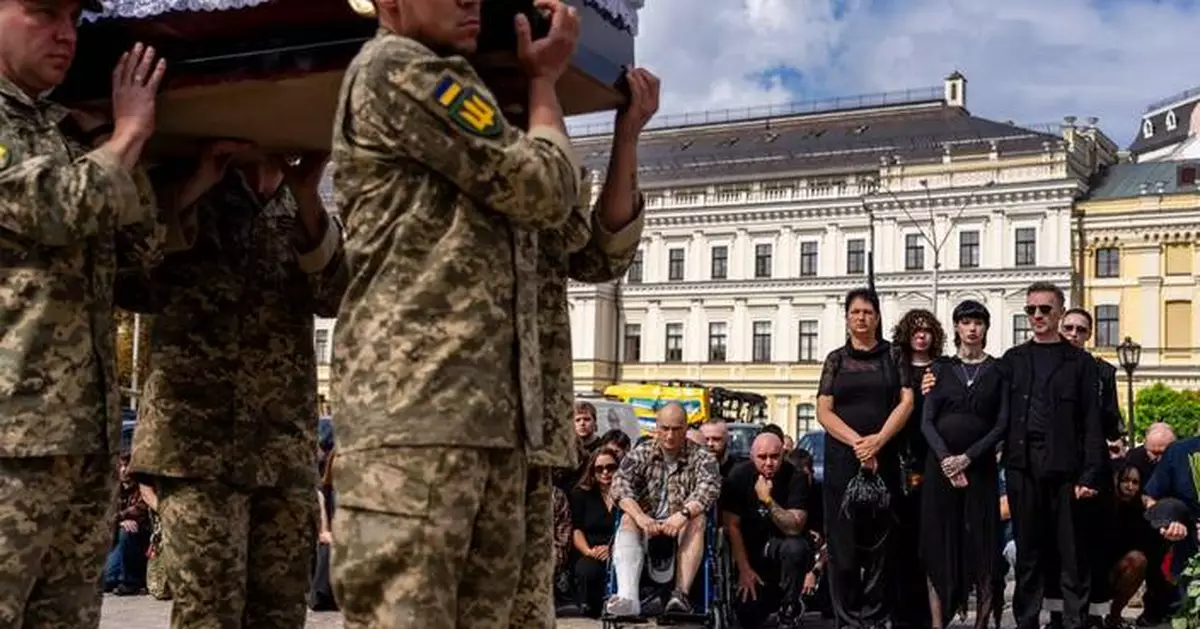 A pregnant soldier mourns her 21-year-old husband at his funeral in Ukraine