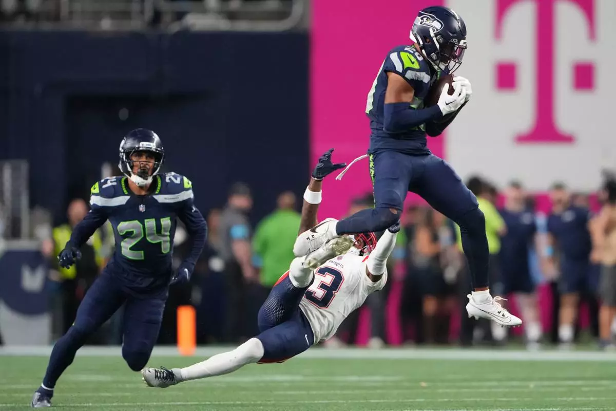 Seattle Seahawks safety Julian Love (20) intercepts a pass intended for New England Patriots wide receiver DeMario Douglas (3) as Seattle Seahawks player Rodney Thomas II (24) looks on during the second half of an NFL football game, Wednesday, Sept. 9, 2026, in Seattle. (AP Photo/Lindsey Wasson) CORRECTION: Corrects player at left to Seattle Seahawks Rodney Thomas II, instead of New England Patriots Dell Pettus