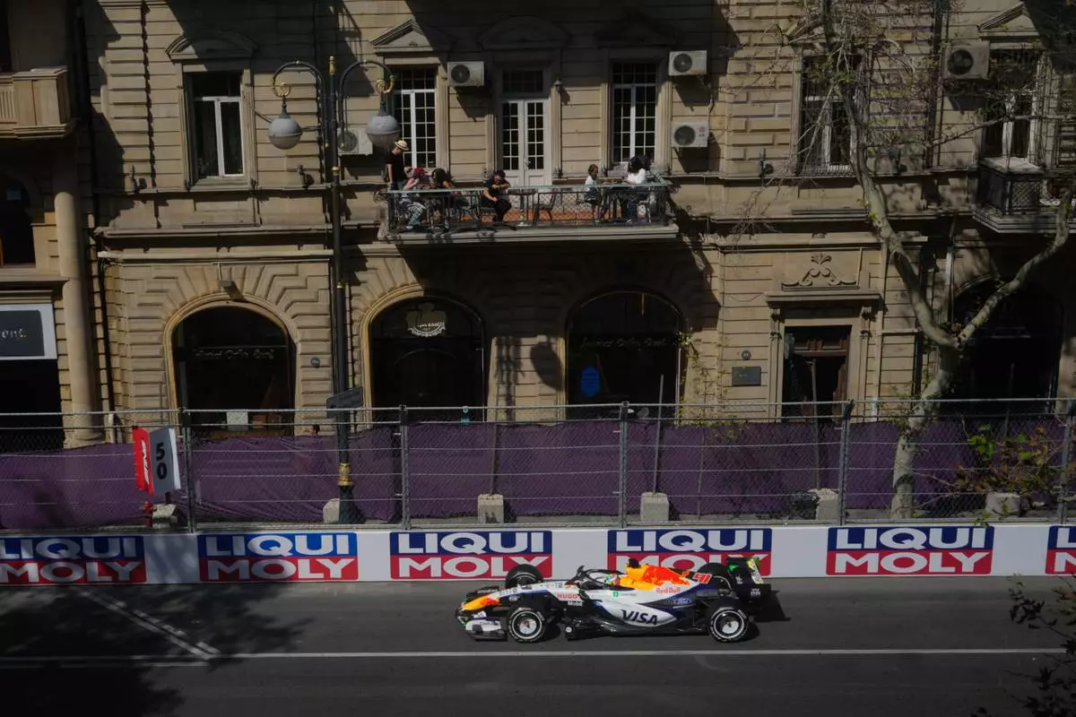 People watch from a balcony as Racing Bulls driver Arvid Lindblad of Britain steers his car during the first free practice ahead of the Azerbaijan F1 Grand Prix, in Baku, Azerbaijan, Thursday, Sept. 24, 2026. (AP Photo/Pavel Bednyakov)