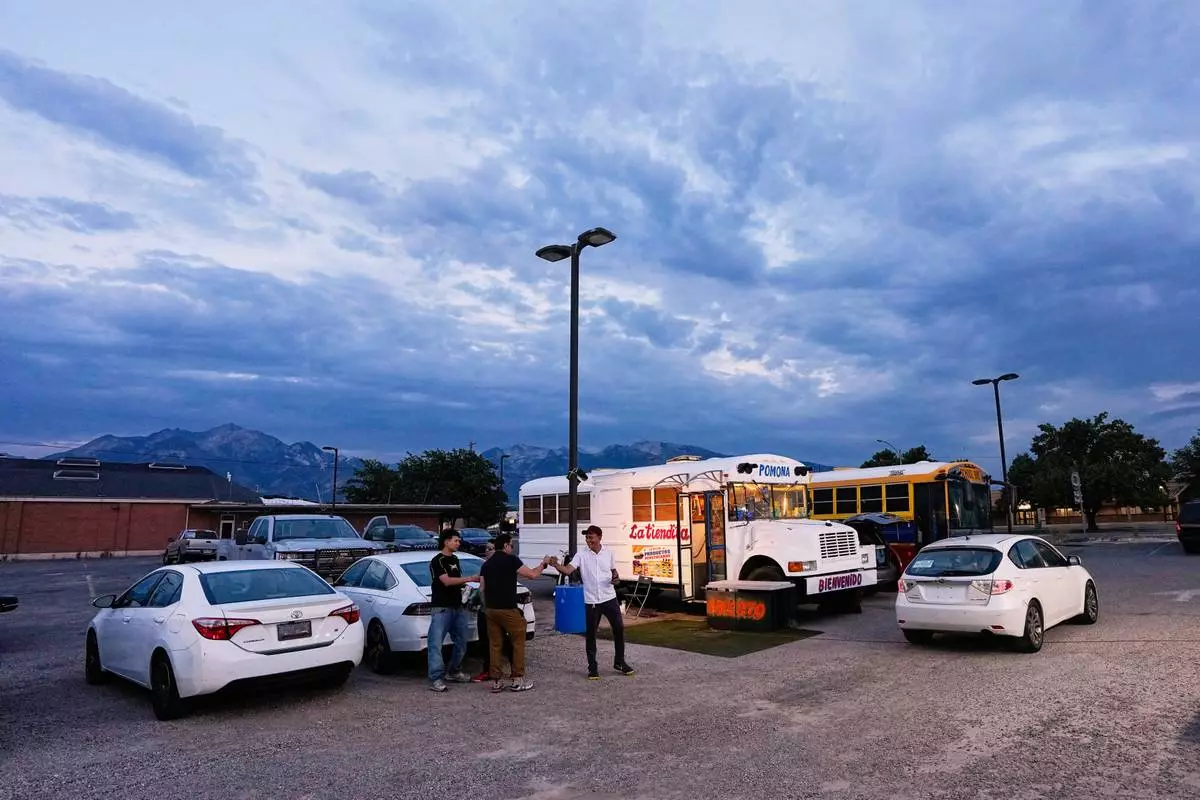 Venezuelan Jadiel Rodriguez greets people in front of his school bus turned store, catering to Venezuelan products Tuesday, July 14, 2026, in Midvale, Utah. (AP Photo/Gregory Bull)