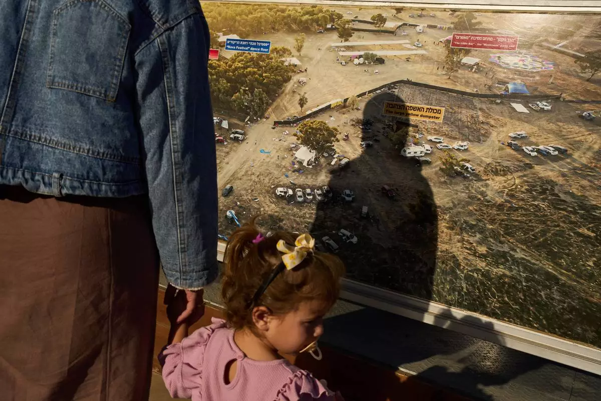 A person's shadow is cast on a large photo of the site of the Nova music festival, taken after hundreds of revelers were killed and abducted there three years prior in the Oct. 7 Hamas attack, on display at the site of the attack near Kibbutz Reim in southern Israel, Friday, Oct. 2, 2026. (AP Photo/Oded Balilty)