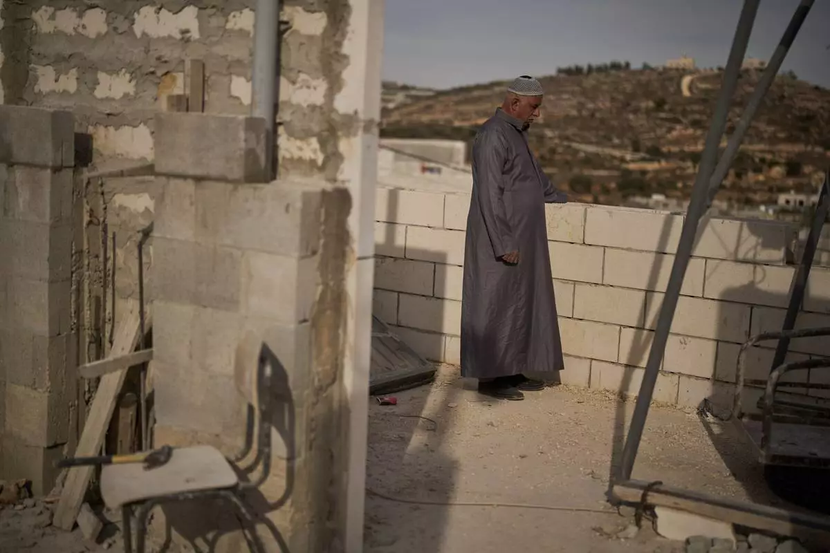 Mahmoud Tubasi stands on a rooftop near his two family's houses, which were burned by Israeli settlers in the West Bank village of Jalud, Tuesday, Oct. 20, 2026. (AP Photo/Leo Correa)