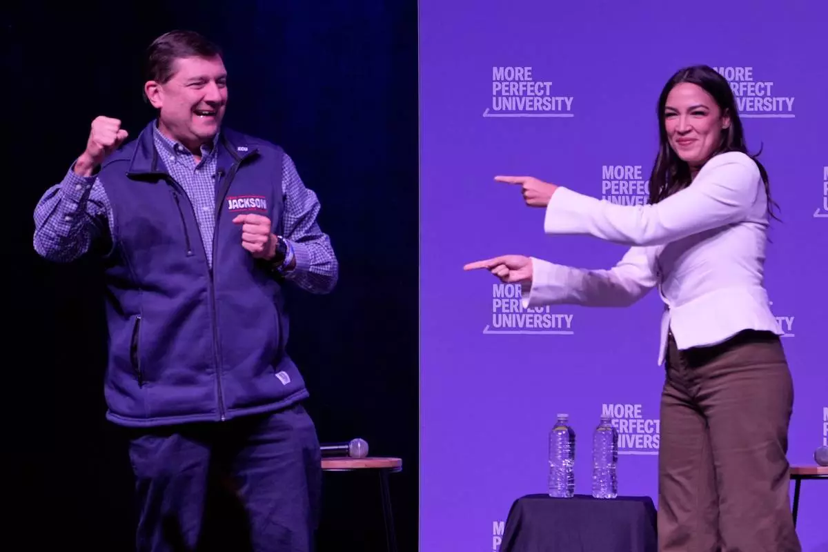 Troy Jackson, Democratic candidate for U.S. Senate, and Rep. Alexandria Ocasio-Cortez, D-N.Y., acknowledge applause at a "Students vs. Billionaires" campaign stop Thursday, Oct. 22, 2026, in Portland, Maine. (AP Photo/Robert F. Bukaty)