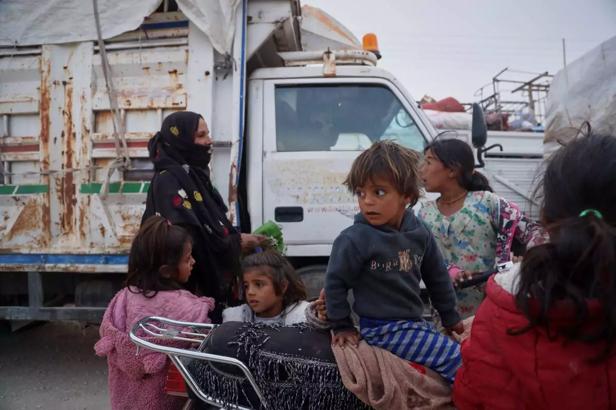 Children gather around a motorcycle as displaced families prepare to leave al-Talayi camp in Hassakeh, Syria, Tuesday, Oct. 13, 2026. Around 450 families are returning to the Ras al-Ayn countryside, seven years after a Turkish military offensive forced them to flee. (AP Photo/Baderkhan Ahmad)