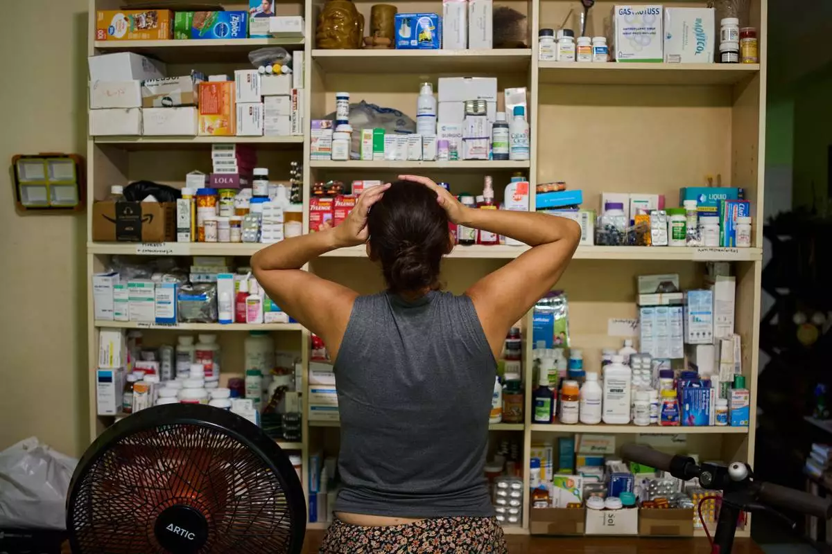 Laura Mendoza, who runs the “Medicine Is Not for Sale” community project, stands in front of a shelf stocked with medicine donated by humanitarian groups for free distribution in Havana, Cuba, Thursday, Oct. 8, 2026. (AP Photo/Ramon Espinosa)