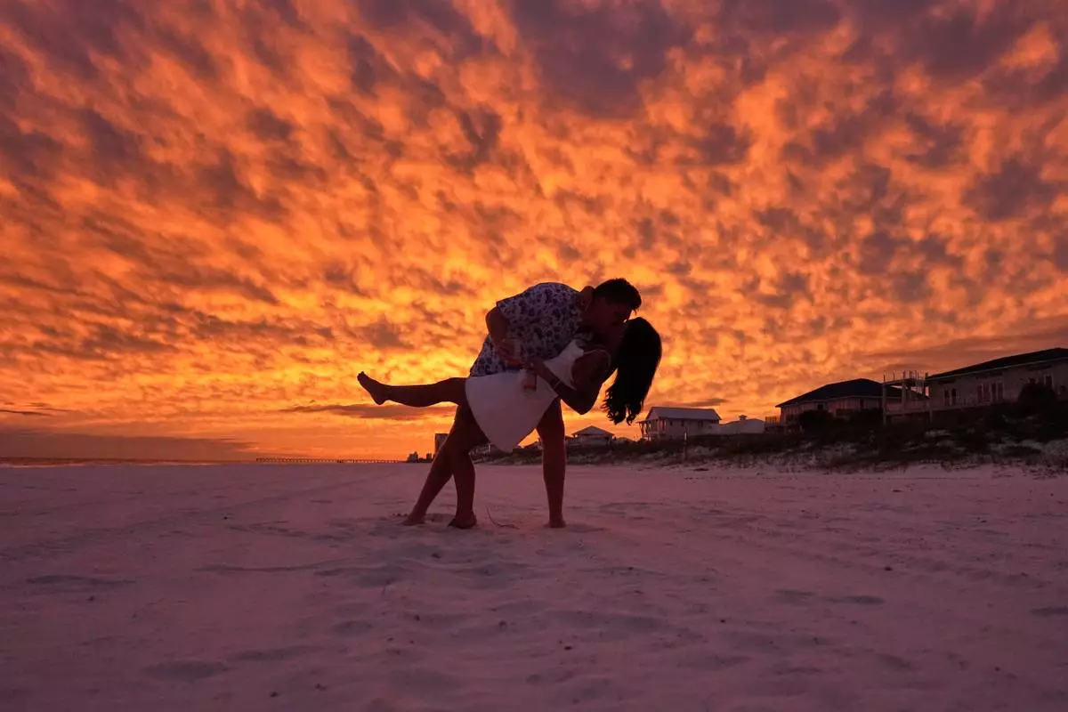 David Pipes and his bride McKenzie Hathoot pose for friends and family, as they just arrived for their wedding weekend, as Hurricane Isaias approaches Pensacola Beach, Fla., Thursday, Oct. 8, 2026. (AP Photo/Gerald Herbert)