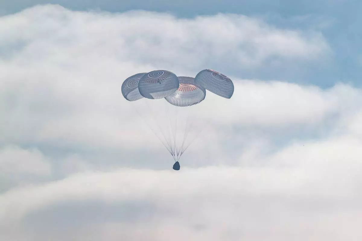 In this photo provided by NASA, the SpaceX Crew Dragon Freedom spacecraft uses parachutes for splashdown in the Pacific Ocean off the coast of California on Thursday, Oct. 8, 2026, returning from the International Space Station. (Keegan Barber/NASA via AP)