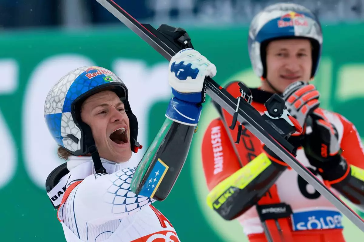 Brazil's Lucas Pinheiro Braathen celebrates winning an alpine ski, men's World Cup giant slalom as third-placed Switzerland's Marco Odermatt applauds in the background, in Soelden, Austria, Sunday, Oct. 25, 2026. (AP Photo/Alessandro Trovati)