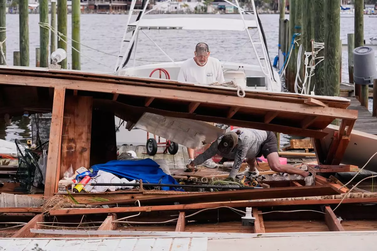 People retrieve belongings from a collapsed boat house in the aftermath of Hurricane Isaias in Destin, Fla., Saturday, Oct. 10, 2026. (AP Photo/Gerald Herbert)