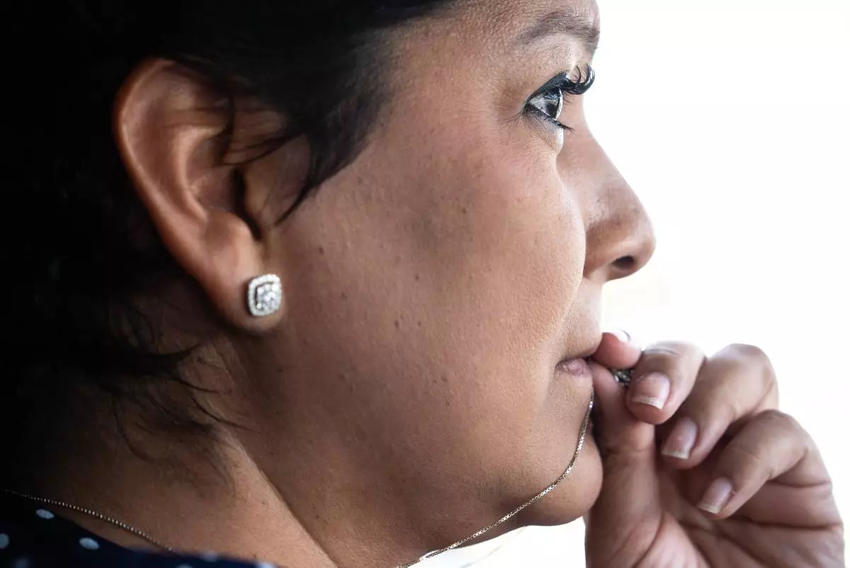 Cindy Banda, who is battling cancer while caring for her sister's kids in addition to her own, holds her necklace as she drives past the house from where her sister, Melissa Banda, was abducted by her ex-husband before he killed her, in McAllen, Texas, Sept. 15, 2026. (AP Photo/Julia Demaree Nikhinson)