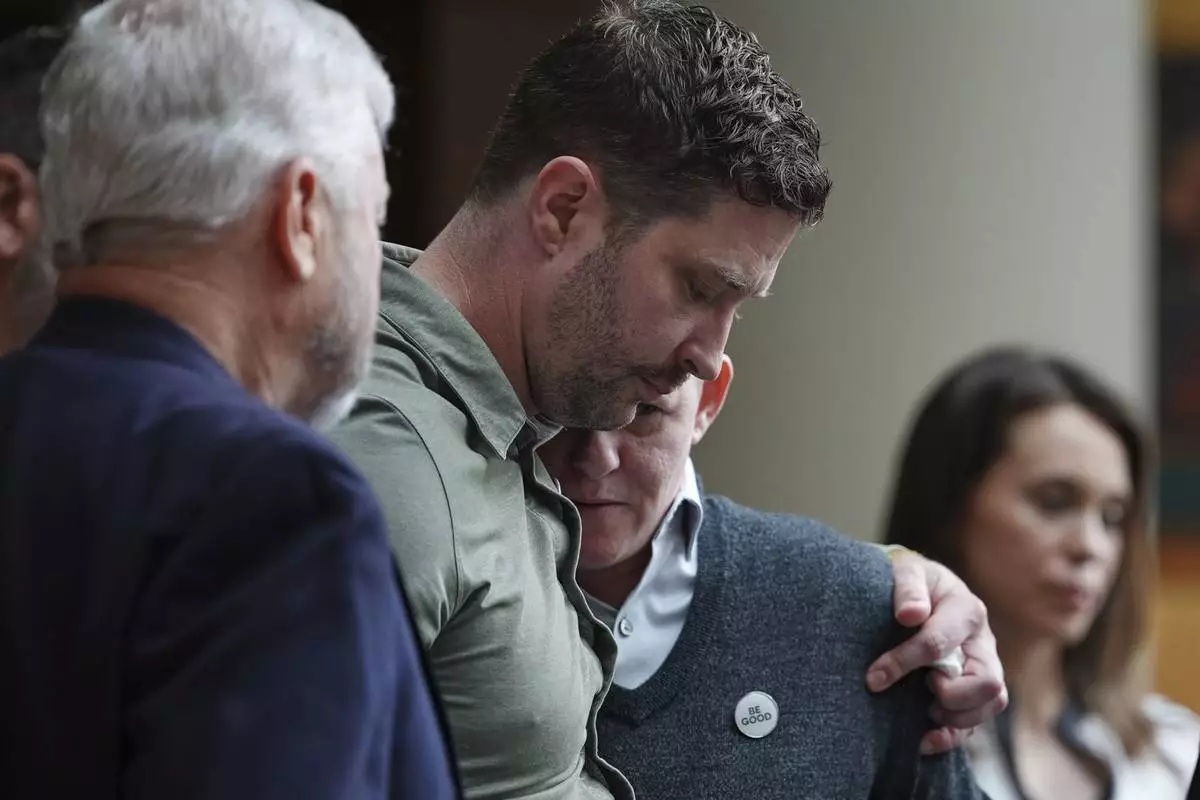 Brent Ganger, center, and Becca Good, right, embrace after speaking during a news conference announcing lawsuits against the U.S. government and immigration officials over the killing of Renee Good, Thursday, Oct. 1, 2026, in Minneapolis. (AP Photo/Ellen Schmidt)