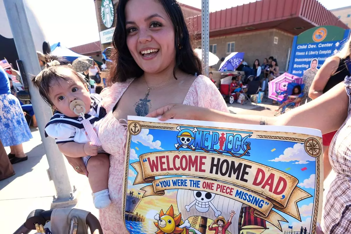 Kathy Monterroso, center, holding her daughter Sarahi Monterroso, waits to greet her husband, sailor Chris Monterroso as the USS Abraham Lincoln aircraft carrier returns to Naval Air Station North Island after deployment Thursday, Oct. 8, 2026, in Coronado, Calif. (AP Photo/Gregory Bull)