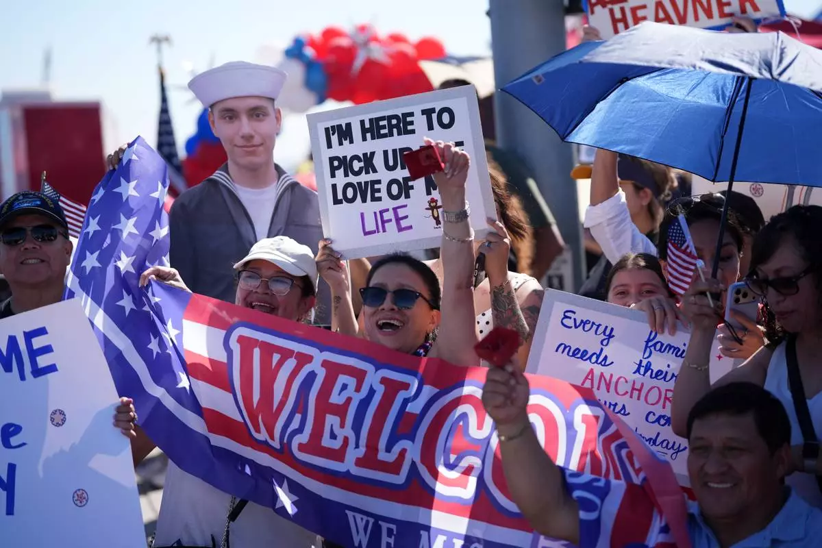Family and friends wait to greet the USS Abraham Lincoln aircraft carrier as it returns to Naval Air Station North Island after deployment Thursday, Oct. 8, 2026, in Coronado, Calif. (AP Photo/Gregory Bull)