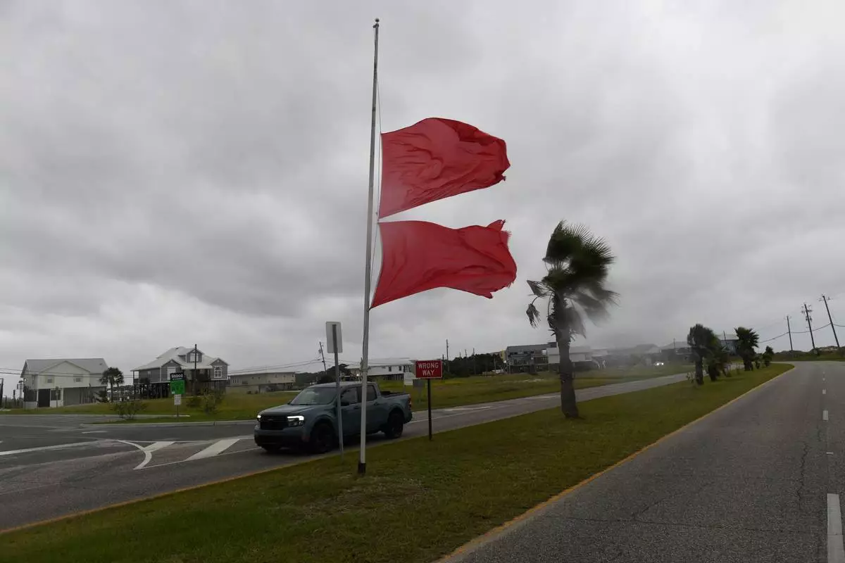 Marine flags flap in the wind generated by the effects of Isaias as a vehicle passes on Friday, Oct. 9, 2026, in Dauphin Island, Ala. (AP Photo/Octavio Jones)