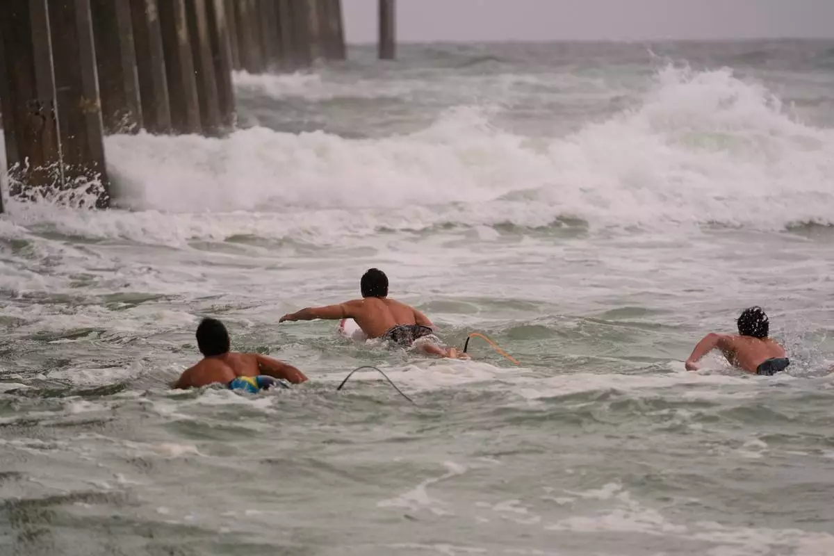 Surfers swim out to waves as Hurricane Isaias approaches Pensacola Beach, Fla., Friday, Oct. 9, 2026. (AP Photo/Gerald Herbert)