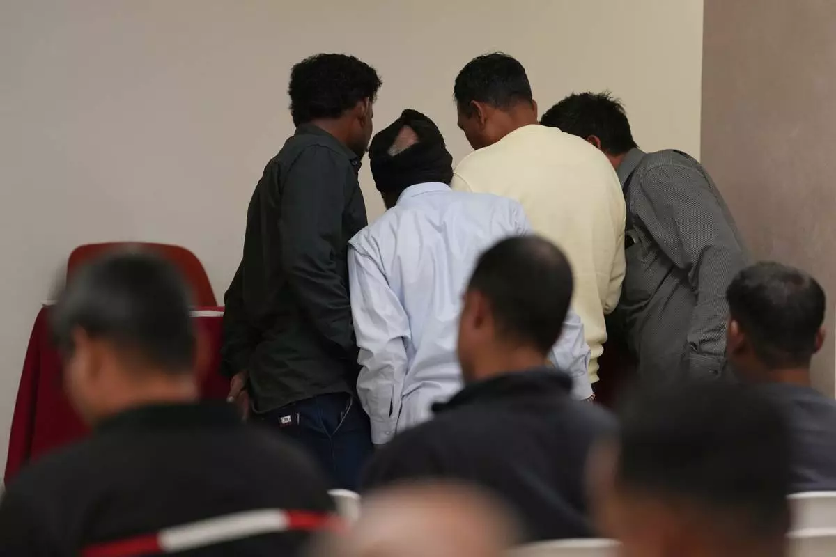 Caddell workers gather in a hotel conference room to wait their turn to sign an agreement for compensation from the U.S. construction company Caddell as part of a settlement into illegal labor practices at a building site for a new U.S. consulate compound in Milan, Italy, Wednesday, Oct. 7, 2026. (AP Photo/Luca Bruno)