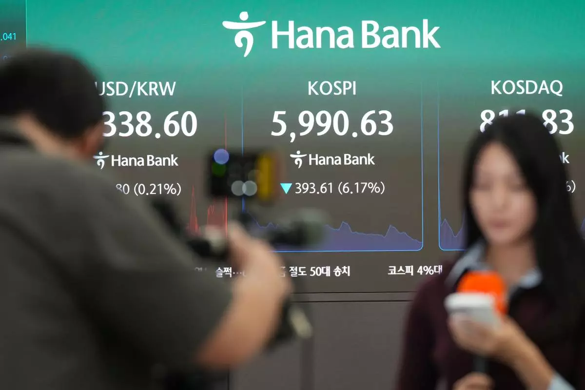 Members of media report near the screens showing the Korea Composite Stock Price Index (KOSPI), the Korean Securities Dealers Automated Quotations (KOSDAQ) and the foreign exchange rate between U.S. dollar and South Korean won at a dealing room of Hana Bank in Seoul, South Korea, Tuesday, Oct. 13, 2026. (AP Photo/Lee Jin-man)