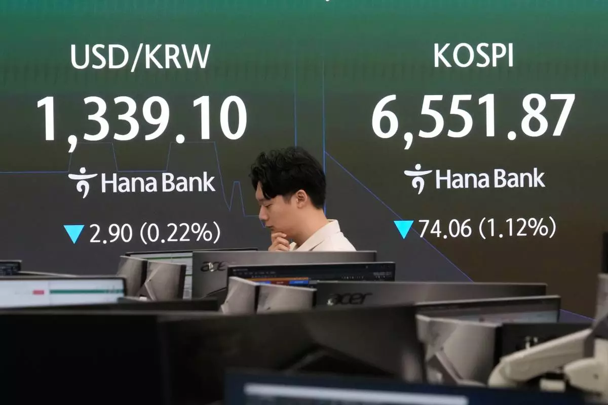 A currency trader passes by a screen showing the Korea Composite Stock Price Index (KOSPI) and the foreign exchange rate between U.S. dollar and South Korean won at the foreign exchange dealing room of the Hana Bank headquarters in Seoul, South Korea, Monday, Oct. 12, 2026. (AP Photo/Ahn Young-joon)