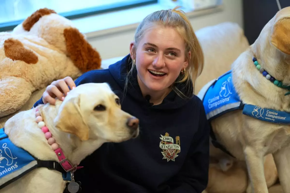 Quinn McEvers, a senior at Evergreen High School, visits with a pair of support dogs named Norene, left, and Polenta at the school Monday, Oct. 5, 2026, in Evergreen, Colo. (AP Photo/David Zalubowski) CORRECTION: Norene, not Noreen