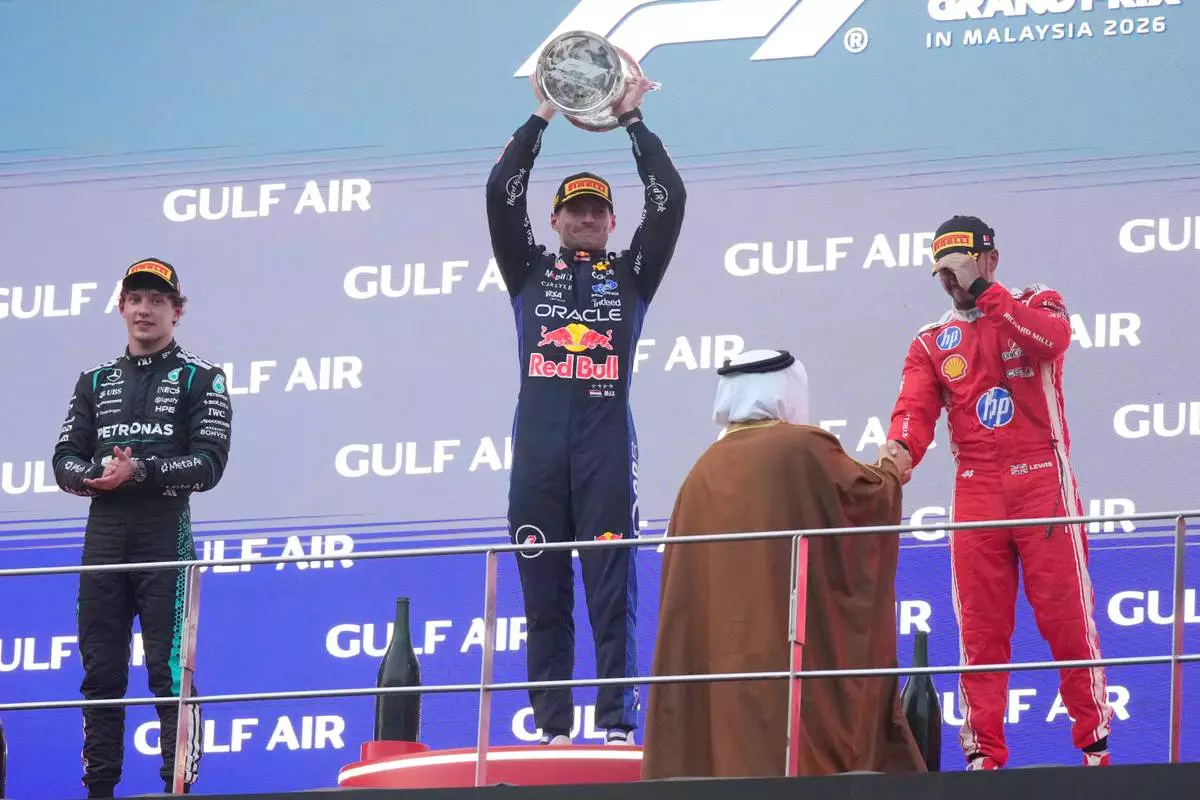 Red Bull driver Max Verstappen of the Netherlands celebrates on the podium flanked by second place Mercedes driver Andrea Kimi Antonelli of Italy, left and third place Ferrari driver Lewis Hamilton of Britain after winning the Bahrain Grand Prix in Sepang, Malaysia, Sunday, Oct. 4, 2026. (AP Photo/Aijaz Rahi)