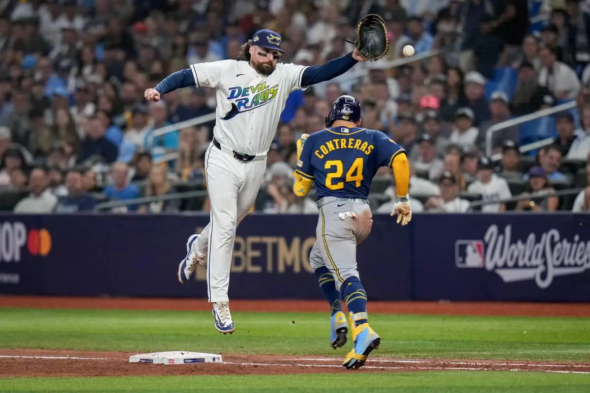 Tampa Bay Rays first baseman Ryan Vilade can't catch a throwing error by third baseman Junior Caminero on a base hit by Milwaukee Brewers catcher William Contreras (24) during the sixth inning of Game 3 of baseball's World Series, Monday, Oct. 26, 2026, in St. Petersburg, Fla., between the Milwaukee Brewers and the Tampa Bay Rays. (AP Photo/Chris O'Meara)