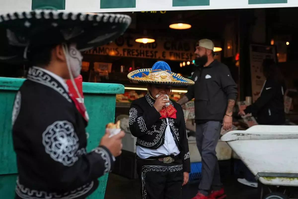 Thomas Santana of Mexican youth folklore dance group Santana Charro Bros., eats a snack in between performances during a Día de Muertos celebration at Pike Place Market, Friday, Oct. 23, 2026, in Seattle. (AP Photo/Lindsey Wasson)