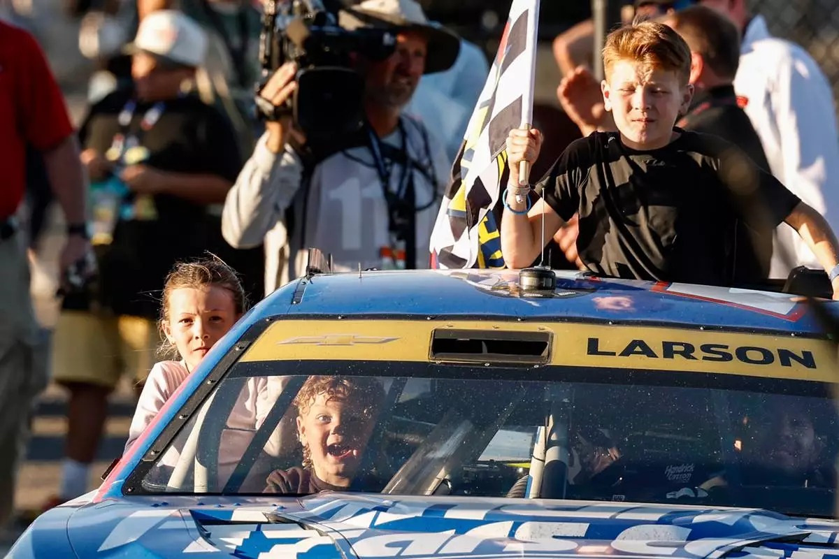 Kyle Larson, bottom right, celebrates with children Owen, Audrey, and Cooper as they ride to Victory Lane after his win in a NASCAR Cup Series auto race, Sunday, Oct. 25, 2026, in Talladega, Ala. (AP Photo/Butch Dill)