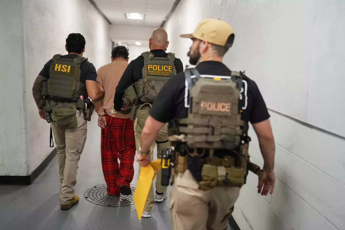 Homeland Security Investigations task force officers escort a suspect accused of illegally registering to vote to a processing facility at Federal Building in Los Angeles, Monday, Oct. 19, 2026. (AP Photo/Jae C. Hong)