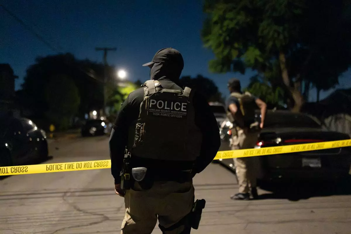A Homeland Security Investigations task force officer stands near police tape marking a perimeter during a federal operation targeting suspected illegal voter registration in Commerce, Calif., Monday, Oct. 19, 2026. (AP Photo/Jae C. Hong)