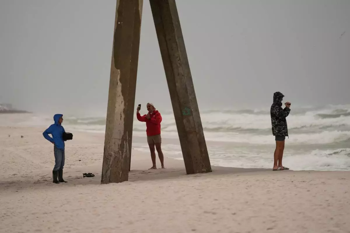 People film the surf as Hurricane Isaias approaches Pensacola Beach, Fla., Friday, Oct. 9, 2026. (AP Photo/Gerald Herbert)