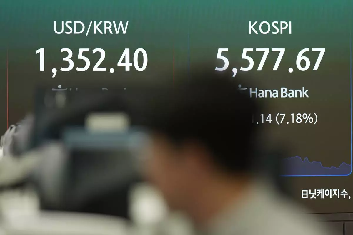 A dealer walks near the screens showing the Korea Composite Stock Price Index (KOSPI) and the foreign exchange rate between U.S. dollar and South Korean won at a dealing room of Hana Bank in Seoul, South Korea, Thursday, Oct. 15, 2026. (AP Photo/Lee Jin-man)