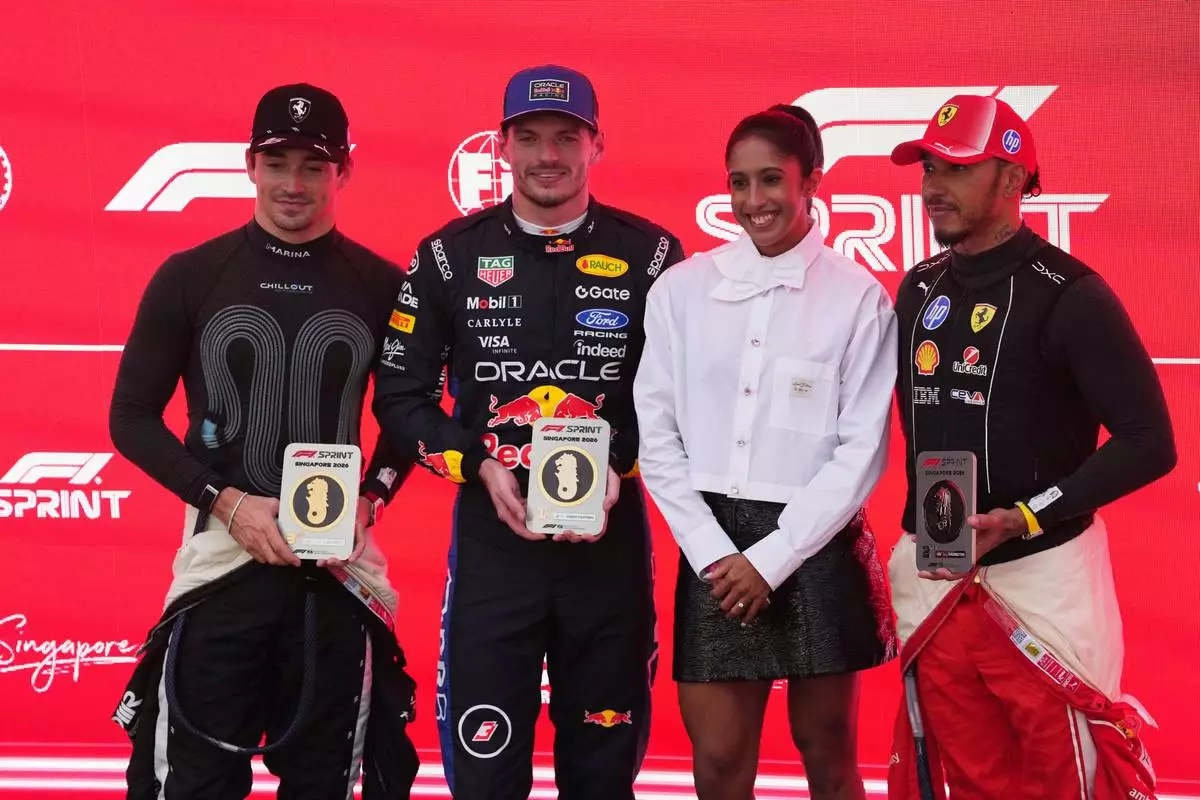 Red Bull driver Max Verstappen of the Netherlands, second left. Ferrari driver Charles Leclerc of Monaco, left, and Ferrari driver Lewis Hamilton of Britain, right, pose after competing in the sprint race ahead of the Singapore Formula One Grand Prix in Singapore, Saturday, Oct. 10, 2026. (AP Photo/Ng Han Guan)