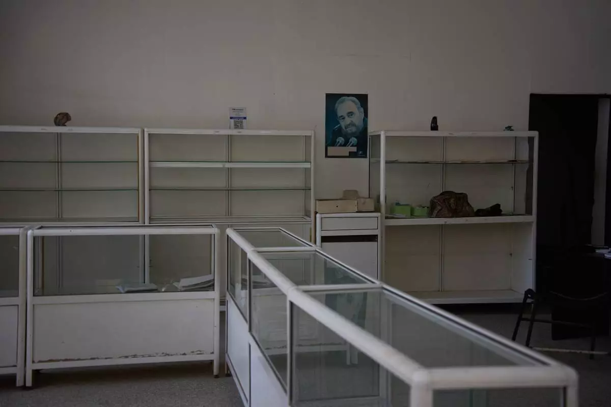 A poster of Fidel Castro hangs on the wall, flanked by empty shelves, at a state-run pharmacy in Havana, Cuba, Thursday, Oct. 8, 2026. (AP Photo/Ramon Espinosa)