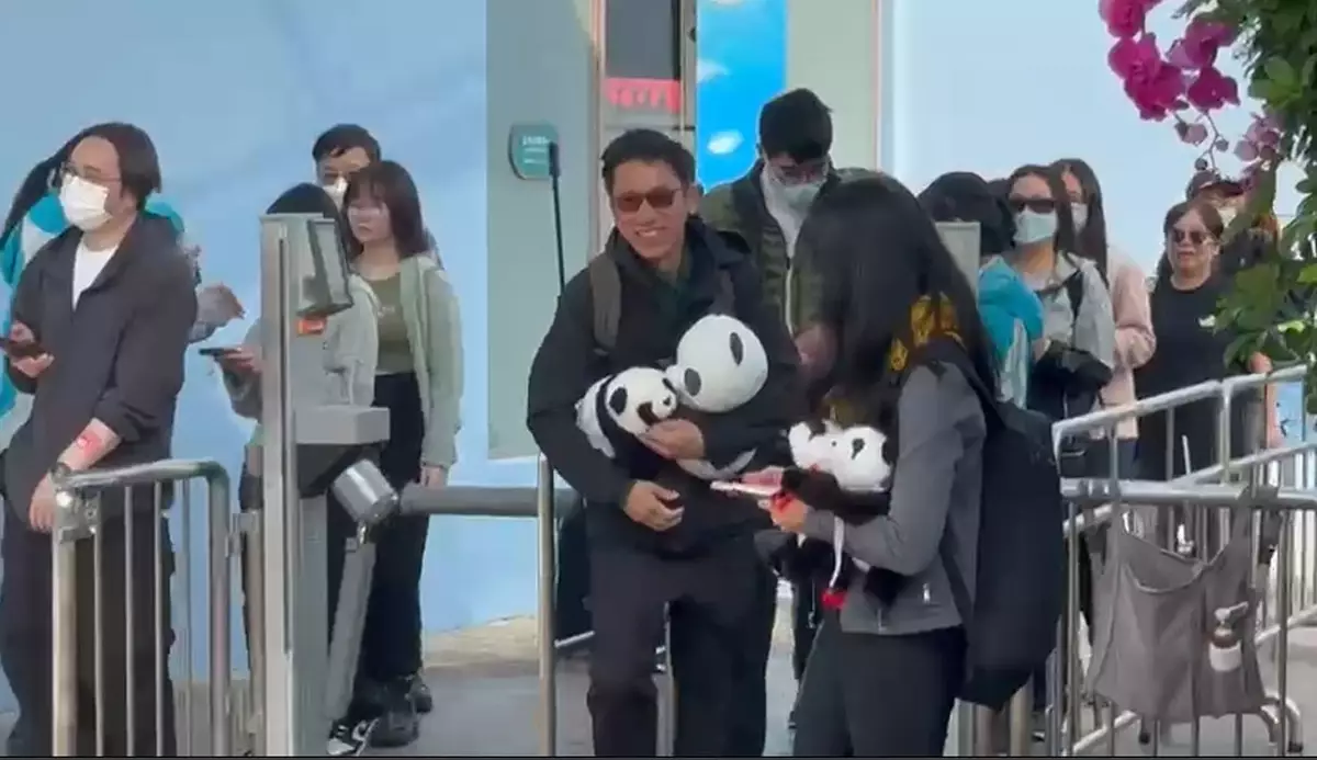 早前受訪的陳先生更大展笑容,揮動手中的熊貓公仔與傳媒打招呼!(巴士的報記者攝)