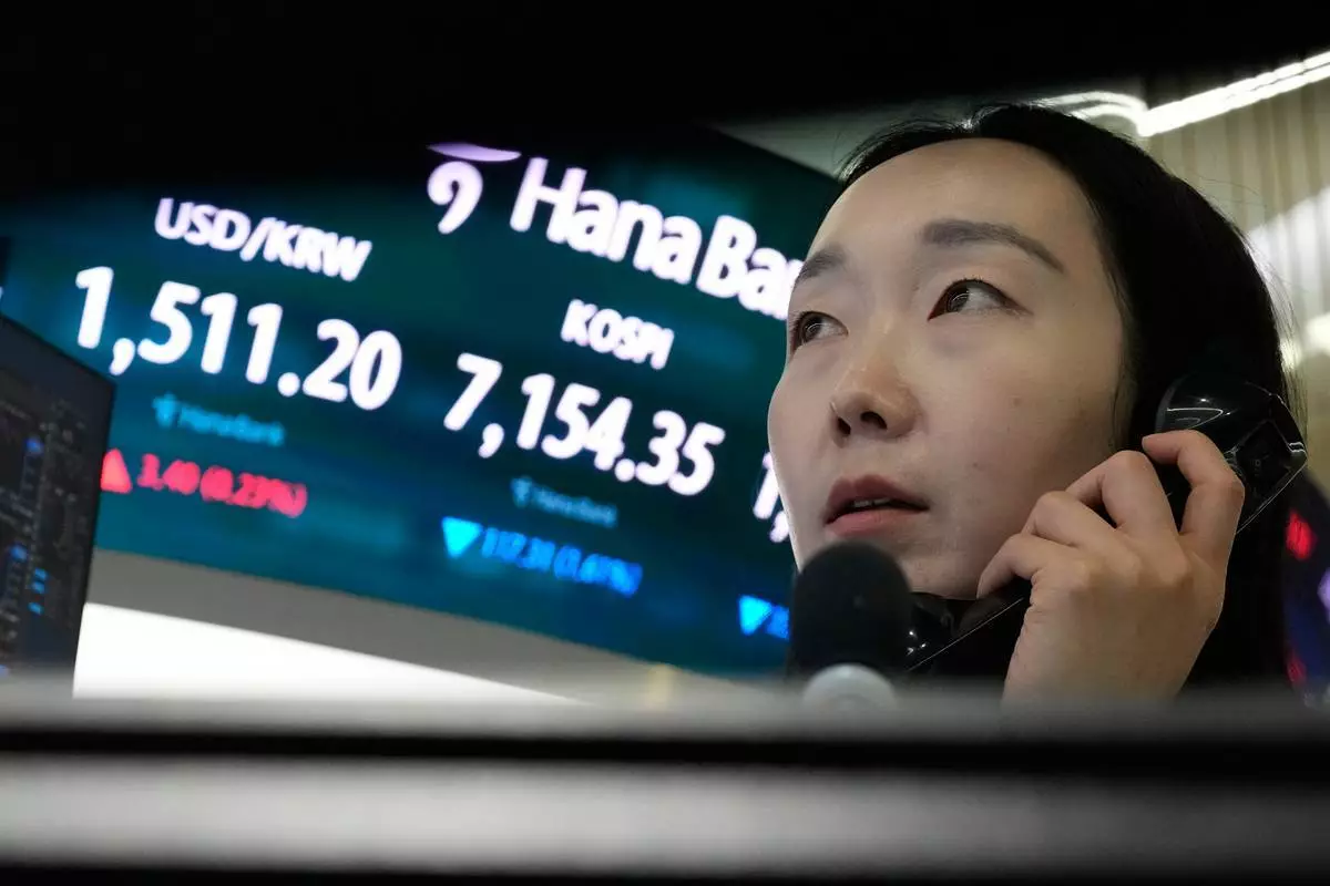 一名外匯交易員周三（2026年5月20日）在南韓首爾韓亞銀行總部外匯交易室，於顯示南韓綜合股價指數（KOSPI）及美元兌南韓圜匯率的屏幕旁通電話。（美聯社圖片/Ahn Young-joon） AP圖片