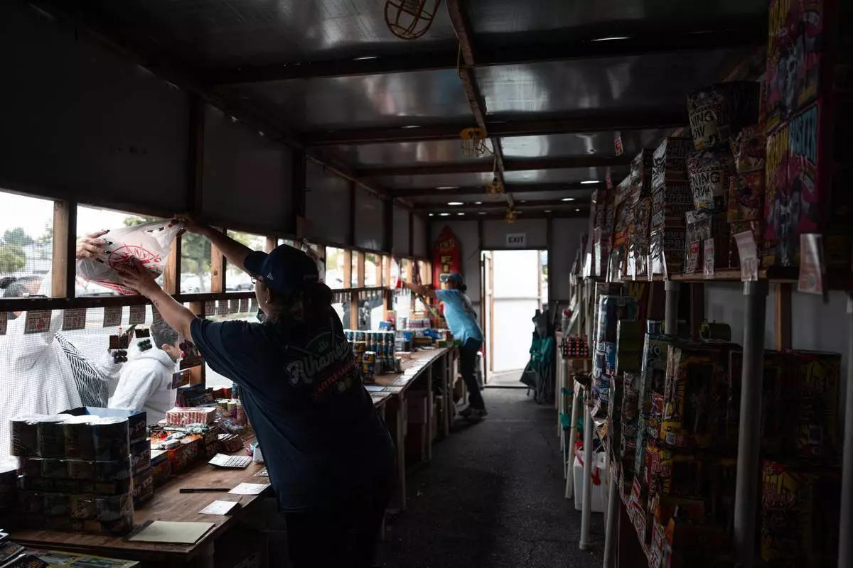 志願者勞倫·卡多薩（前）及珍妮花·阿拉貢於2026年6月30日周二，在加州阿罕布拉的一個TNT煙花攤位工作，為獨立日假期作準備。(美聯社圖片/Jae C. Hong) AP圖片