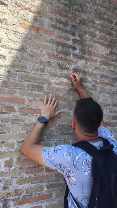 網上流傳影片顯示，一名男子在羅馬鬥獸場石牆刻字。