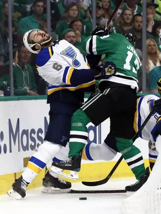 St. Louis Blues' Joel Edmundson (6) recoils after being hit by Dallas Stars' Mattias Janmark, of Sweden, while fighting for control of a loose puck along the boards during the first period in Game 6 of an NHL second-round hockey playoff series, Sunday, May 5, 2019, in Dallas. (AP PhotoTony Gutierrez)