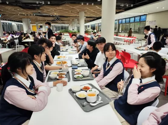 民心學校學生跟香港同學在飯堂共進晚餐，分享國內生活點滴。