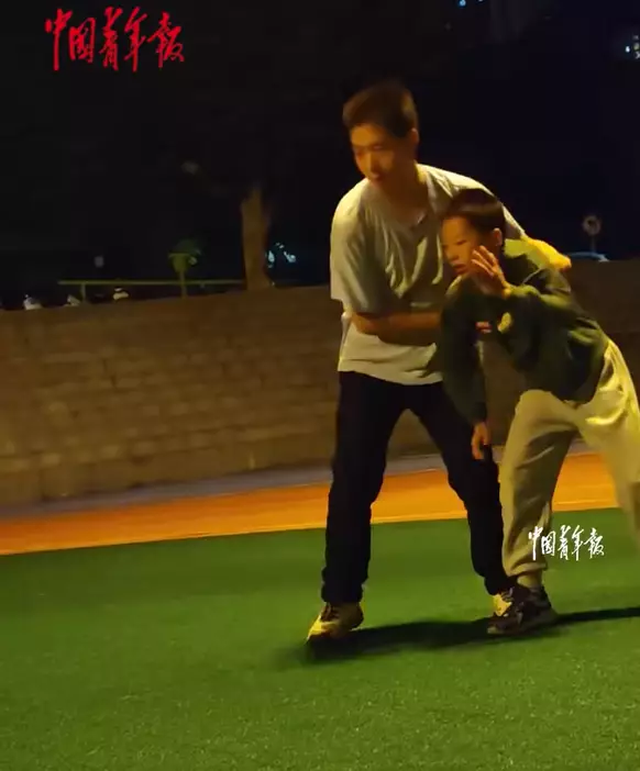 男孩首次參加跳遠比賽，父親以「托舉」陪練助他建立動作與信心。「人民日報香港」FB影片截圖