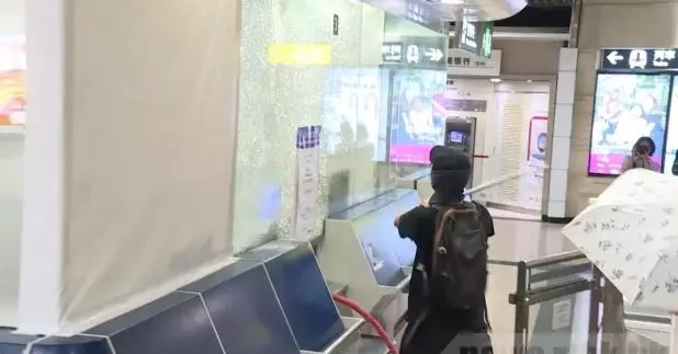 有黑衣蒙面人破壞沙田港鐵站客務中心的玻璃。（關銘輝攝）