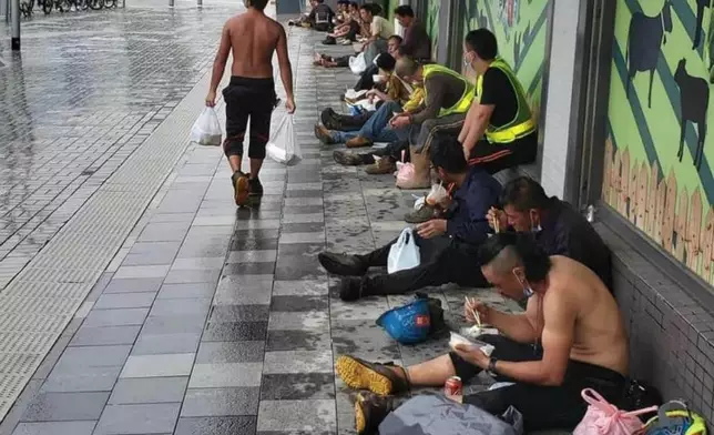 一條長街，天雨路濕，坐滿食飯工友。