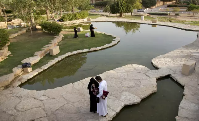 In this March 8, 2018 photo, visitors walk in a garden at the 18th century Diriyah fortified complex, that once served as the seat of power for the ruling Al Saud, in Riyadh, Saudi Arabia. (AP Photo/Amr Nabil)