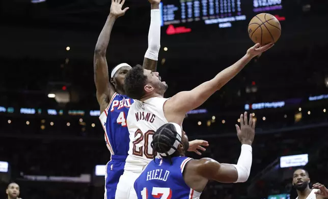 Cleveland Cavaliers forward Georges Niang (20) shoots against Philadelphia 76ers guard Buddy Hield (17) and forward Paul Reed during the second half of an NBA basketball game Friday, March 29, 2024, in Cleveland. (AP Photo/Ron Schwane)