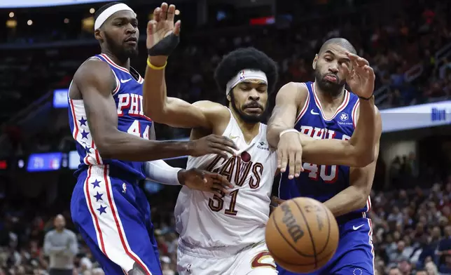 Cleveland Cavaliers center Jarrett Allen (31) and Philadelphia 76ers forward Paul Reed (44) and forward Nicolas Batum (40) try for a rebound during the second half of an NBA basketball game Friday, March 29, 2024, in Cleveland. (AP Photo/Ron Schwane)