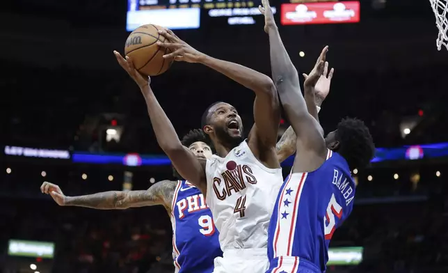 Cleveland Cavaliers forward Evan Mobley (4) shoots against Philadelphia 76ers center Mo Bamba (5) and guard Kelly Oubre Jr. (9) during the second half of an NBA basketball game Friday, March 29, 2024, in Cleveland. (AP Photo/Ron Schwane)